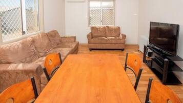 A living room with a wooden dining table, two sofas, and a television.