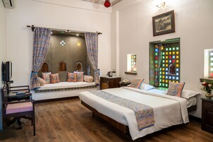 Un dormitorio con dos camas, suelo de madera, una ventana con luces de colores y un cuadro colgado en la pared.