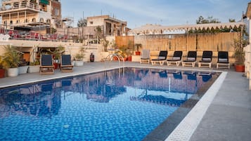 A swimming pool with lounge chairs and potted plants.