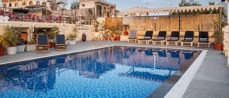 A swimming pool with lounge chairs and potted plants.
