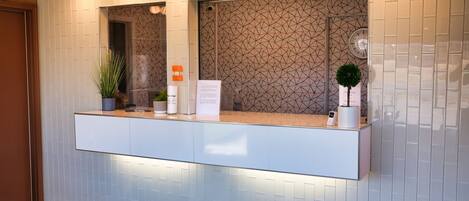 A reception area with a counter, a large mirror, and a patterned wall.