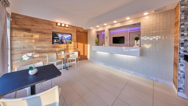 A modern hotel lobby with a reception desk, seating area, and a TV mounted on the wall. - Regency Inn (Eddyville)