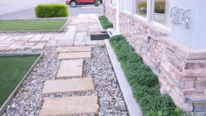 A landscaped pathway leading to a building with a stone facade and a number plaque. - Regency Inn (Eddyville)