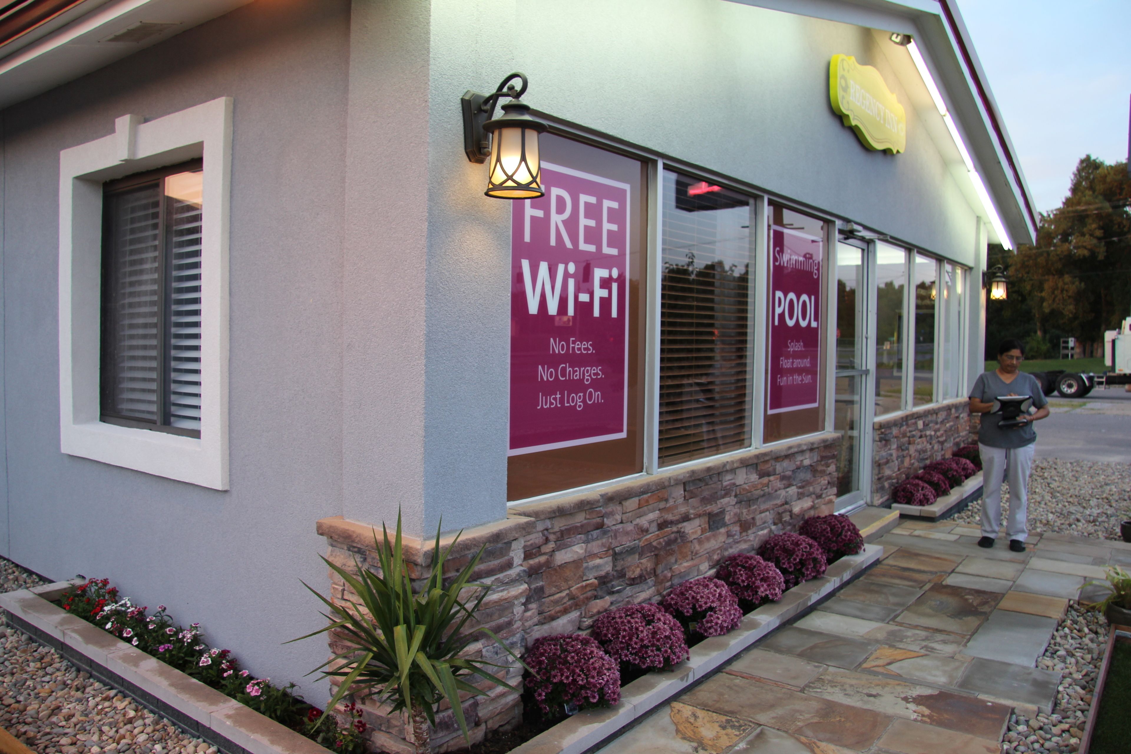 Un edifici amb un cartell de 'FREE Wi-Fi', un cartell de 'POOL' i una persona que hi fa servir.