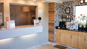 A modern reception area with a counter, a clock, and a coffee machine. - Regency Inn (Eddyville)