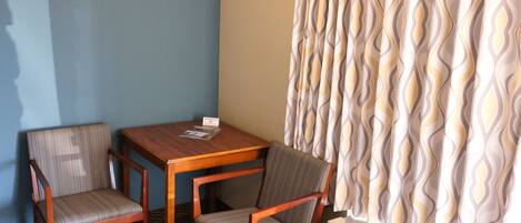 A room with two wooden chairs, a small table, and a patterned curtain.