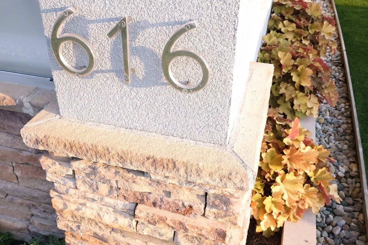 Un numéro de maison, le « 616 », est fixé sur un mur de pierre, lui-même reposant sur des fondations en pierre.