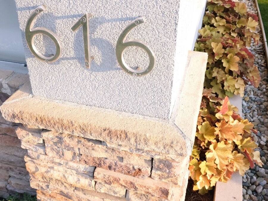 Un numéro de maison, le « 616 », est fixé sur un mur de pierre, lui-même reposant sur des fondations en pierre.