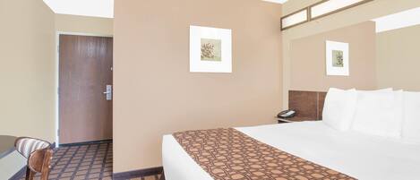 A hotel room with a bed, a chair, a desk, and a telephone.