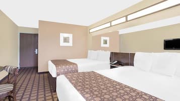 A hotel room with two beds, a desk, a chair, and a television.