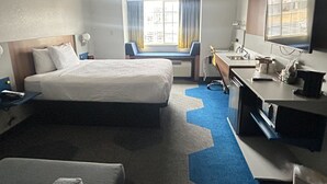 A hotel room with a large bed, a desk with a chair, a television, and a window with curtains. - Microtel Inn & Suites by Wyndham Mansfield (Mansfield)