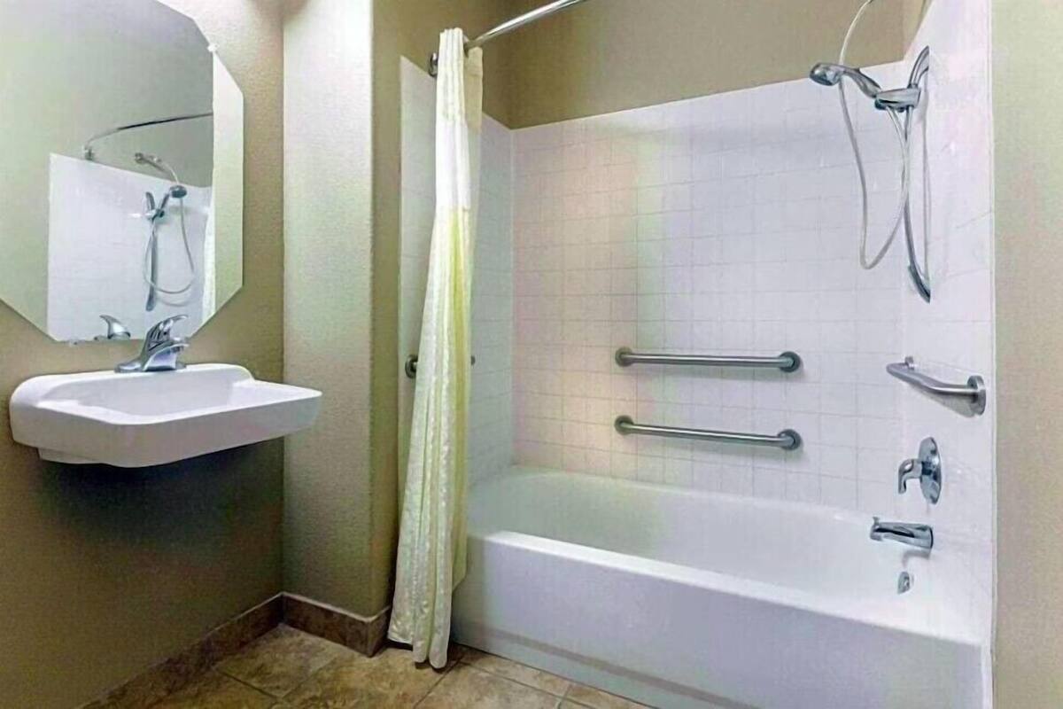 A bathroom with a bathtub, a shower, a sink, and a mirror.