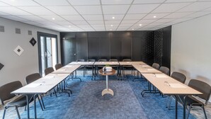 Ein Konferenzraum mit langem Tisch, Stühlen, einem Projektor und Teppichboden.