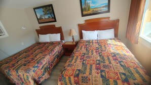 A room with two beds, each with a patterned bedspread and white pillows. There is a painting on the wall above the beds and a window with curtains to the right. - Relax Inn Collingwood (Collingwood)