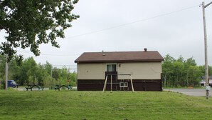 A single-story mobile home with a brown roof and beige siding, located on a grassy area with a picnic table and a ladder in front. - Relax Inn Collingwood (Collingwood)