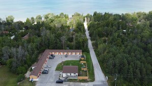 An aerial view of a motel with a parking lot, a small lawn, and a road leading to a forested area. - Relax Inn Collingwood (Collingwood)