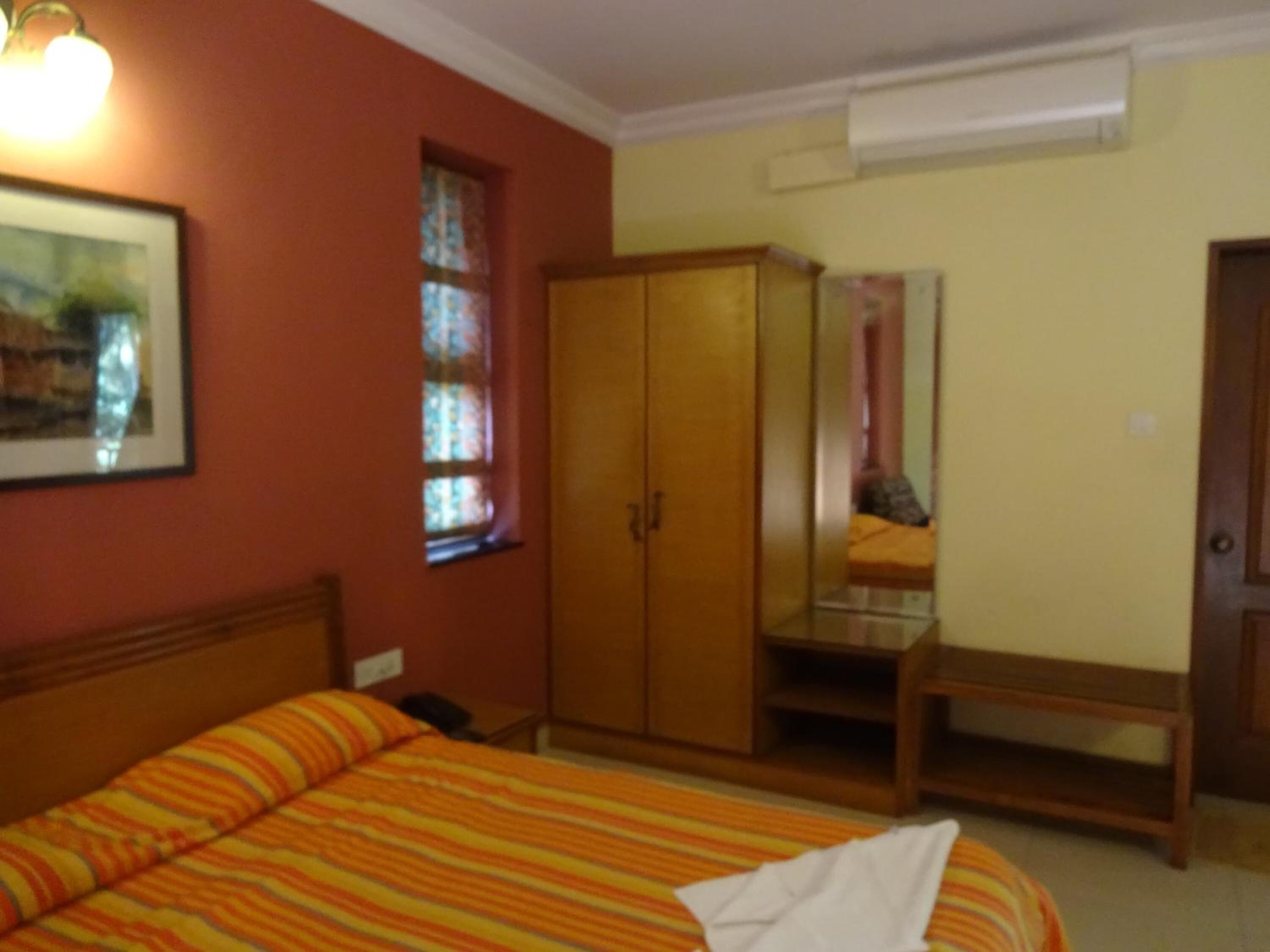 Ein Schlafzimmer mit Bett, Kleiderschrank, kleinem Tisch und Fenster.