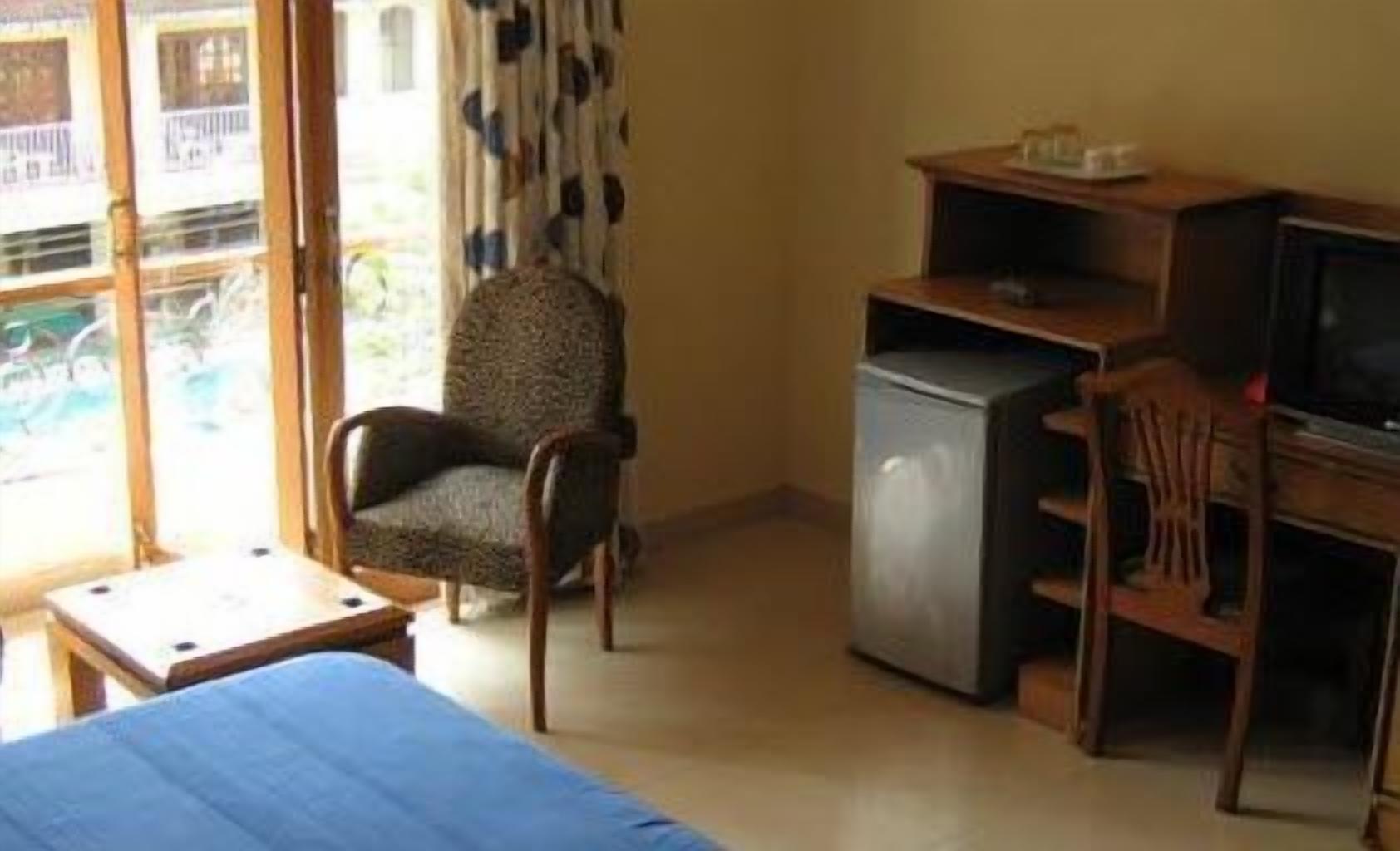 Ein Zimmer mit einem Bett, einem Sessel, einem Schreibtisch mit Computer und einem Fernseher.