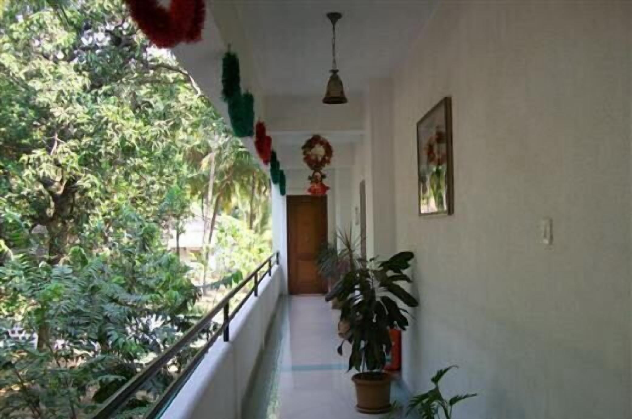 A corridor with a railing, potted plants, and a hanging decoration.