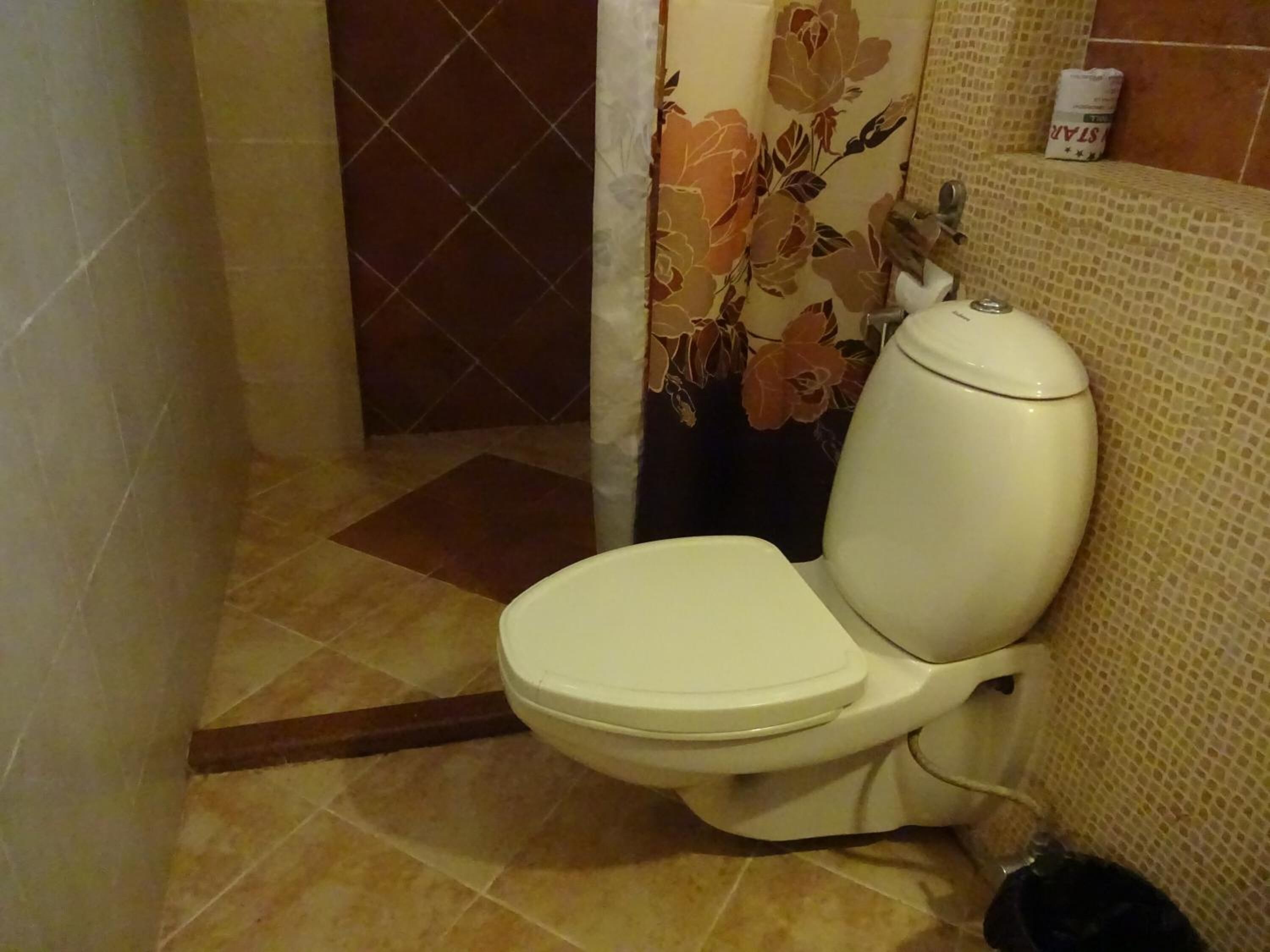 A bathroom with a toilet, a shower curtain, and tiled walls.
