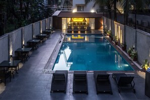 A poolside area with lounge chairs and tables, a bar, and a pool. - Hotel Calangute Towers (Calangute)