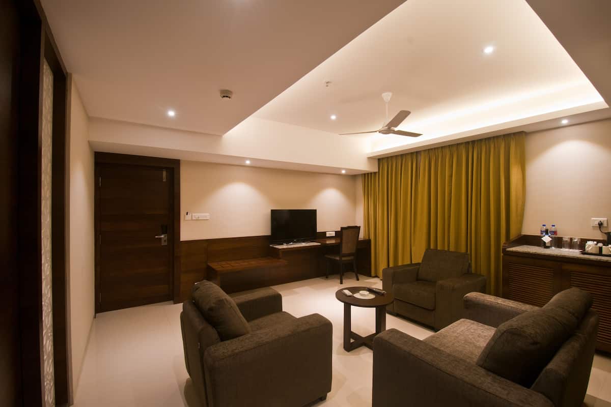 A modern living room with a flat-screen TV, a sofa set, a coffee table, and a ceiling fan.
