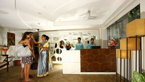 A reception area with a modern design, including a reception desk, seating area, and decorative elements like plants and artwork. - Hotel Calangute Towers (Calangute)