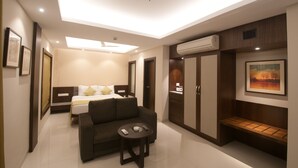 A modern hotel room with a bed, a sofa, a small table, and a bench. - Hotel Calangute Towers (Calangute)
