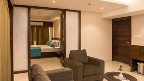 A modern hotel room with a sofa, armchair, and a small table with a vase. - Hotel Calangute Towers (Calangute)