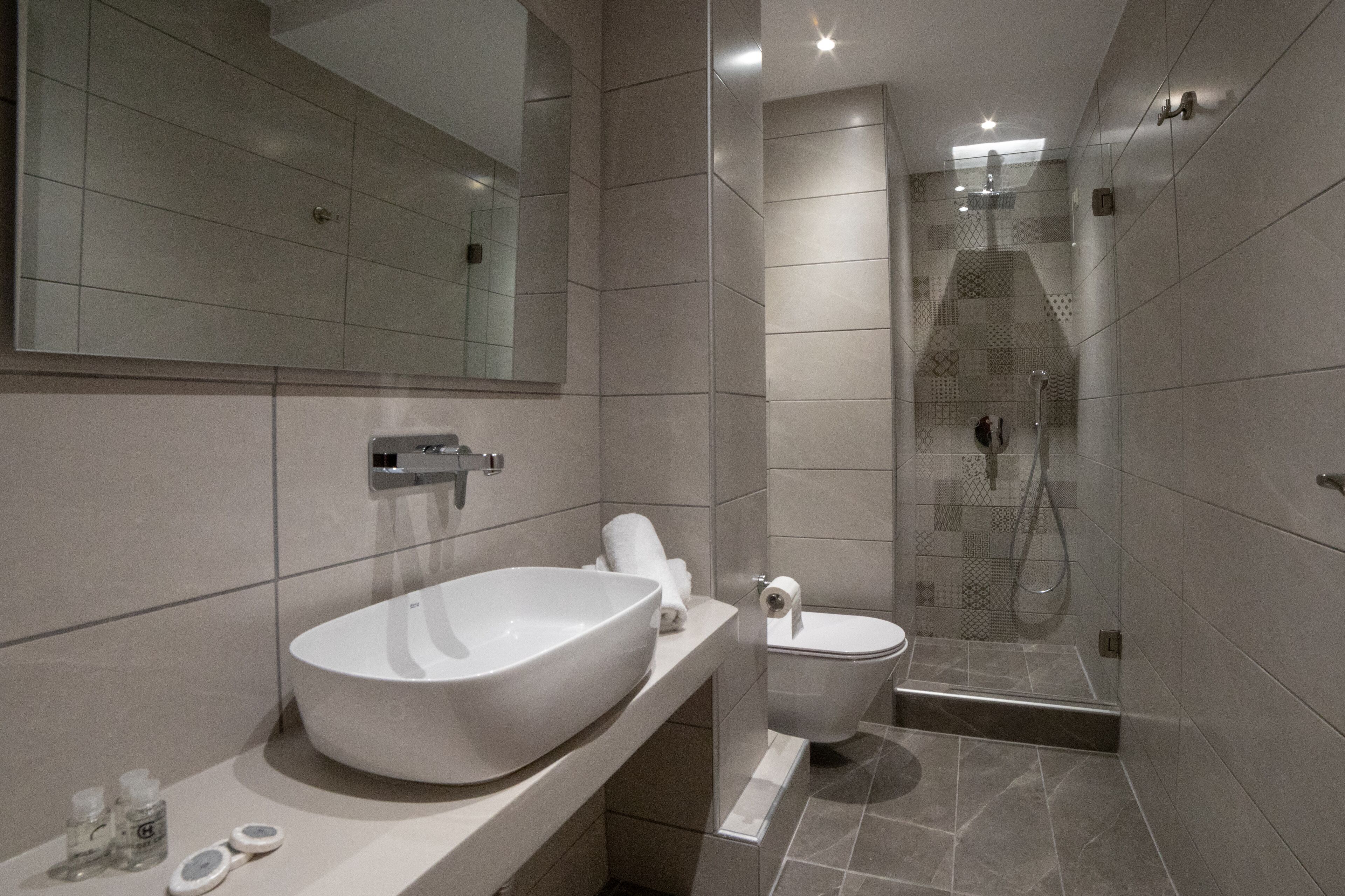 Een moderne badkamer met een groot wit wastafelmeubel, een toilet en een douchecabine met glazen wanden.