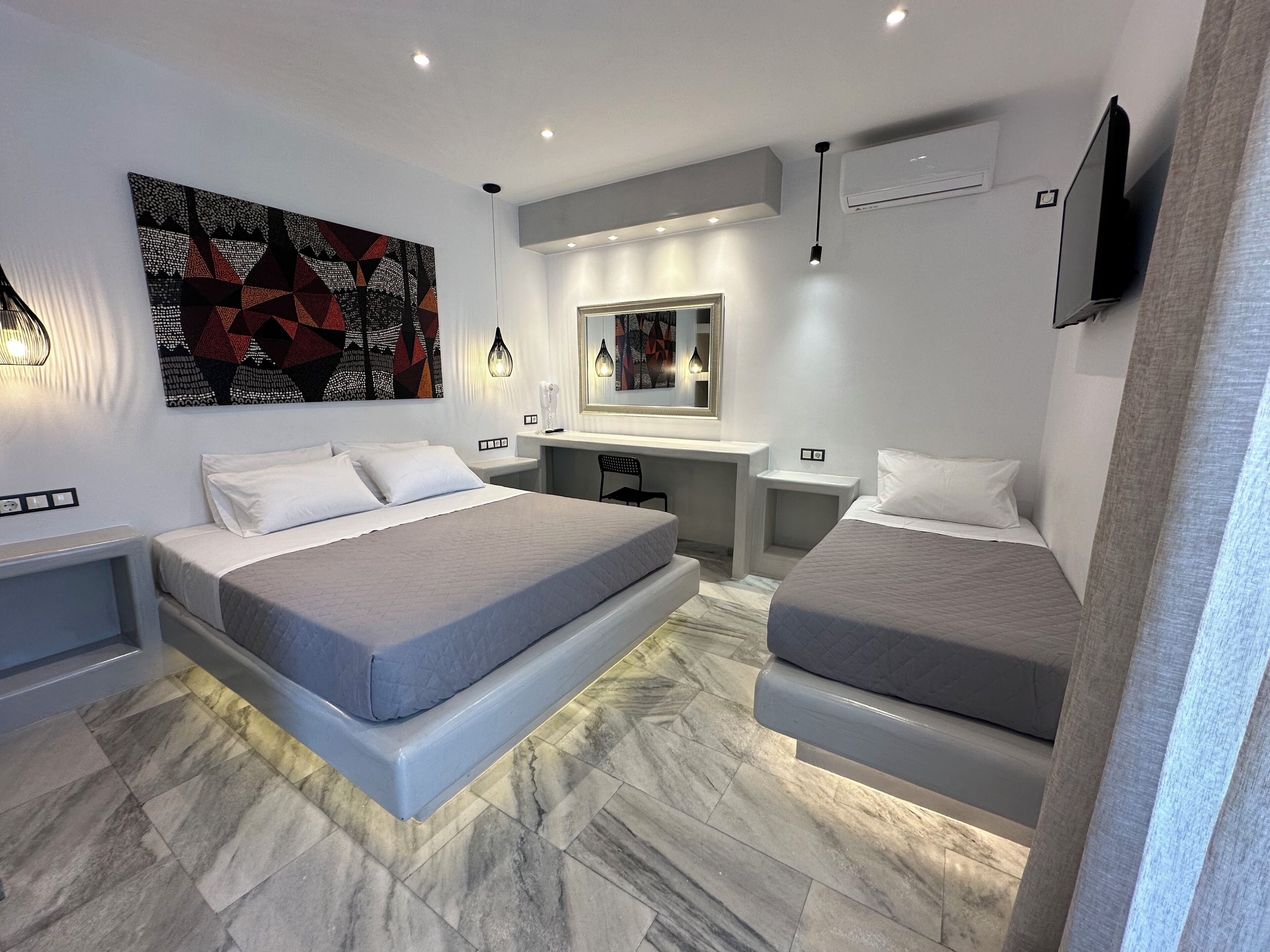 Una camera da letto moderna con due letti, una scrivania e un grande quadro astratto.