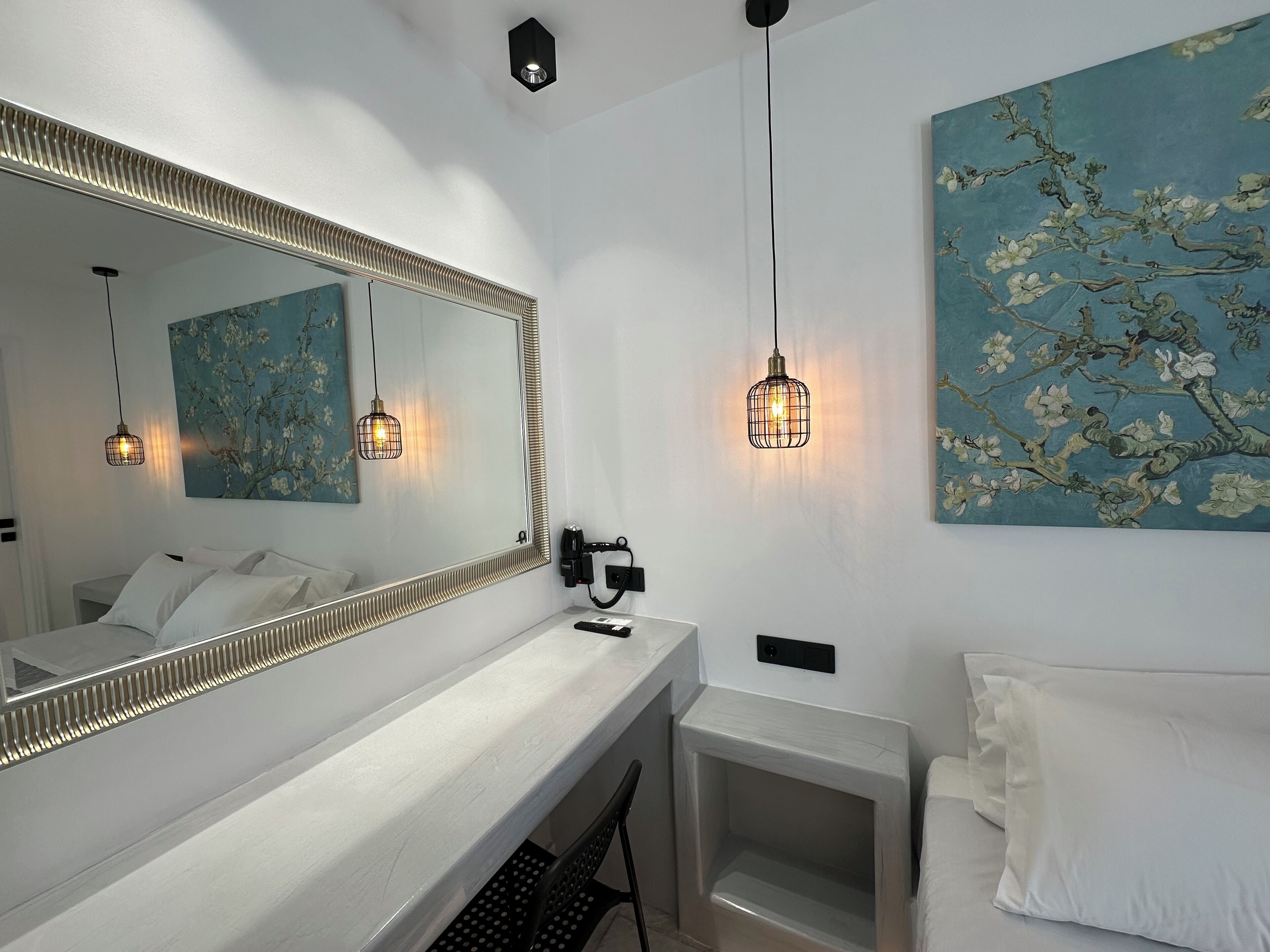 Un baño moderno con un espejo grande, luces colgantes y un cuadro con motivos florales en la pared.