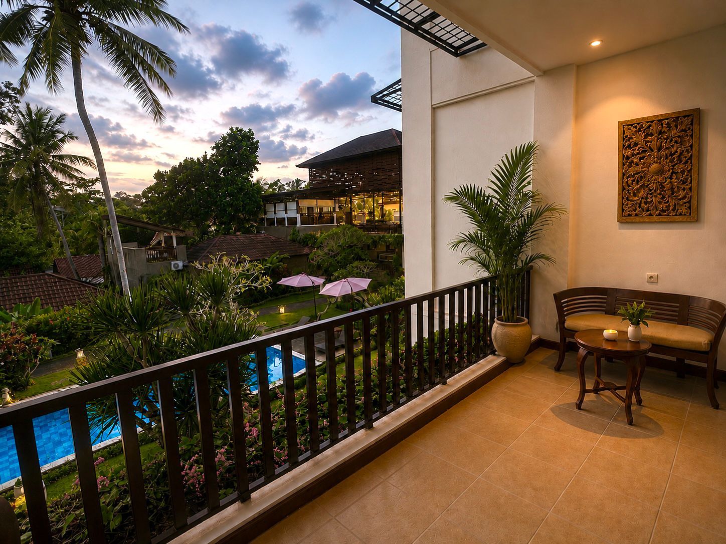 A balcony with a pool, surrounded by tropical plants and a wooden fence.