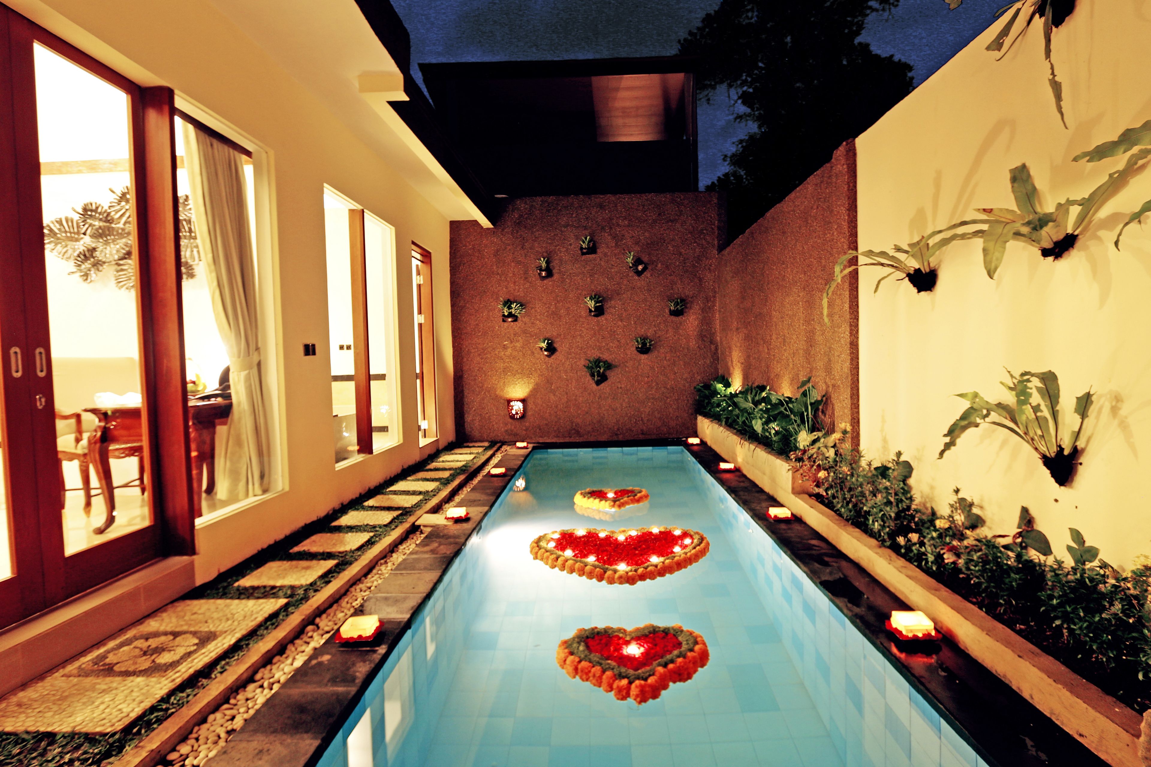 Una piscina con arreglos florales con forma de corazón y plantas en macetas a lo largo de las paredes.