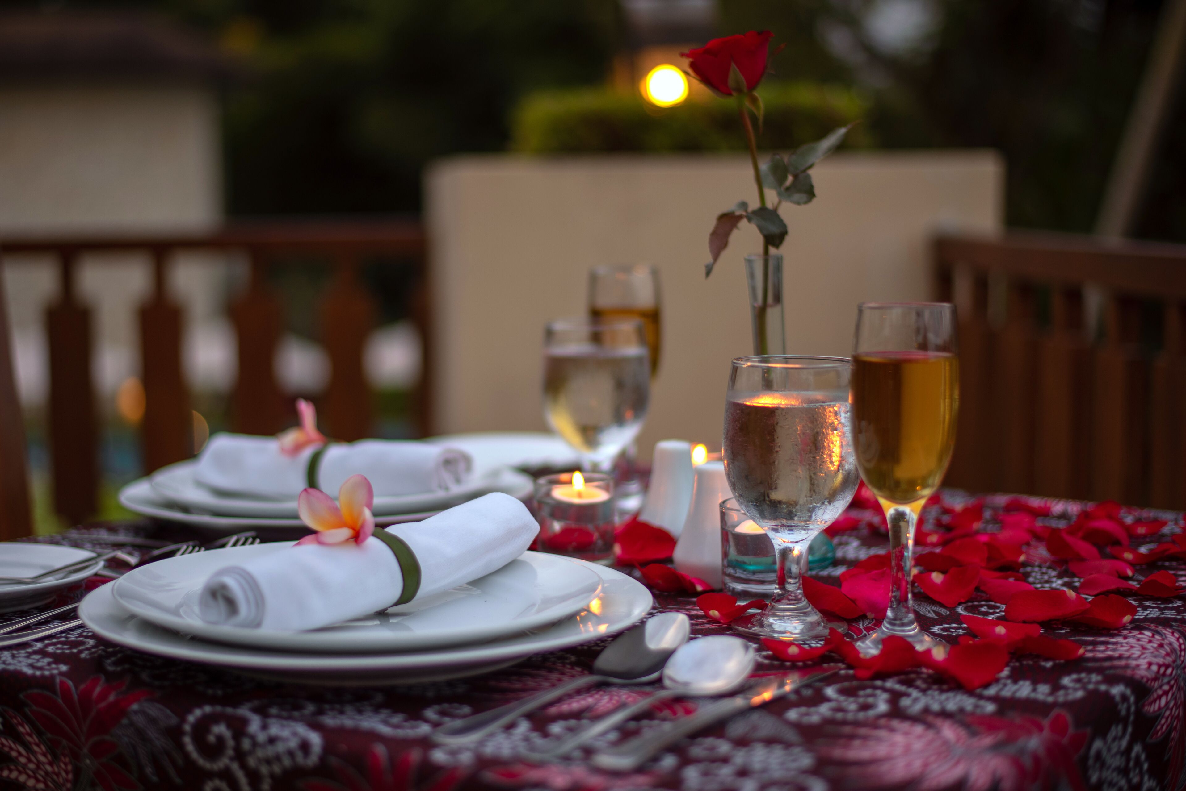 Ein Tisch, festlich gedeckt für ein romantisches Abendessen, mit Kerzen, Rosenblüten und einer Rosenblumen-Mitte.