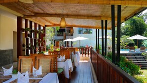 An outdoor dining area with wooden tables, white tablecloths, and umbrellas. - Ashoka Tree Resort at Tanggayuda, Ubud (Ubud)