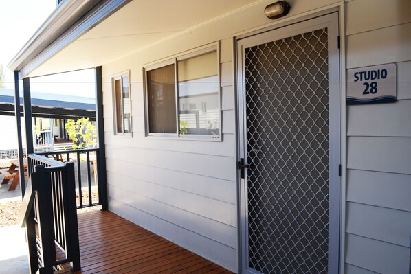 A white building with a wooden deck, a covered patio, and a door labeled "STUDIO 28".