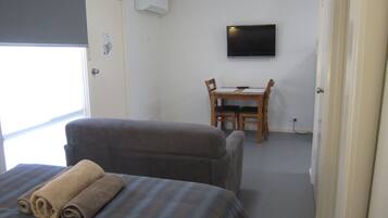 A hotel room with a bed, a chair, a desk, and a television on the wall.