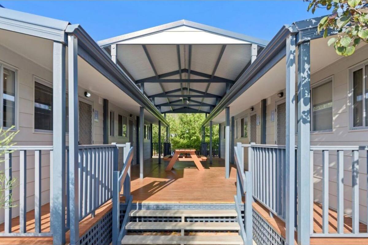 A covered outdoor area with a wooden deck, benches, and railings.