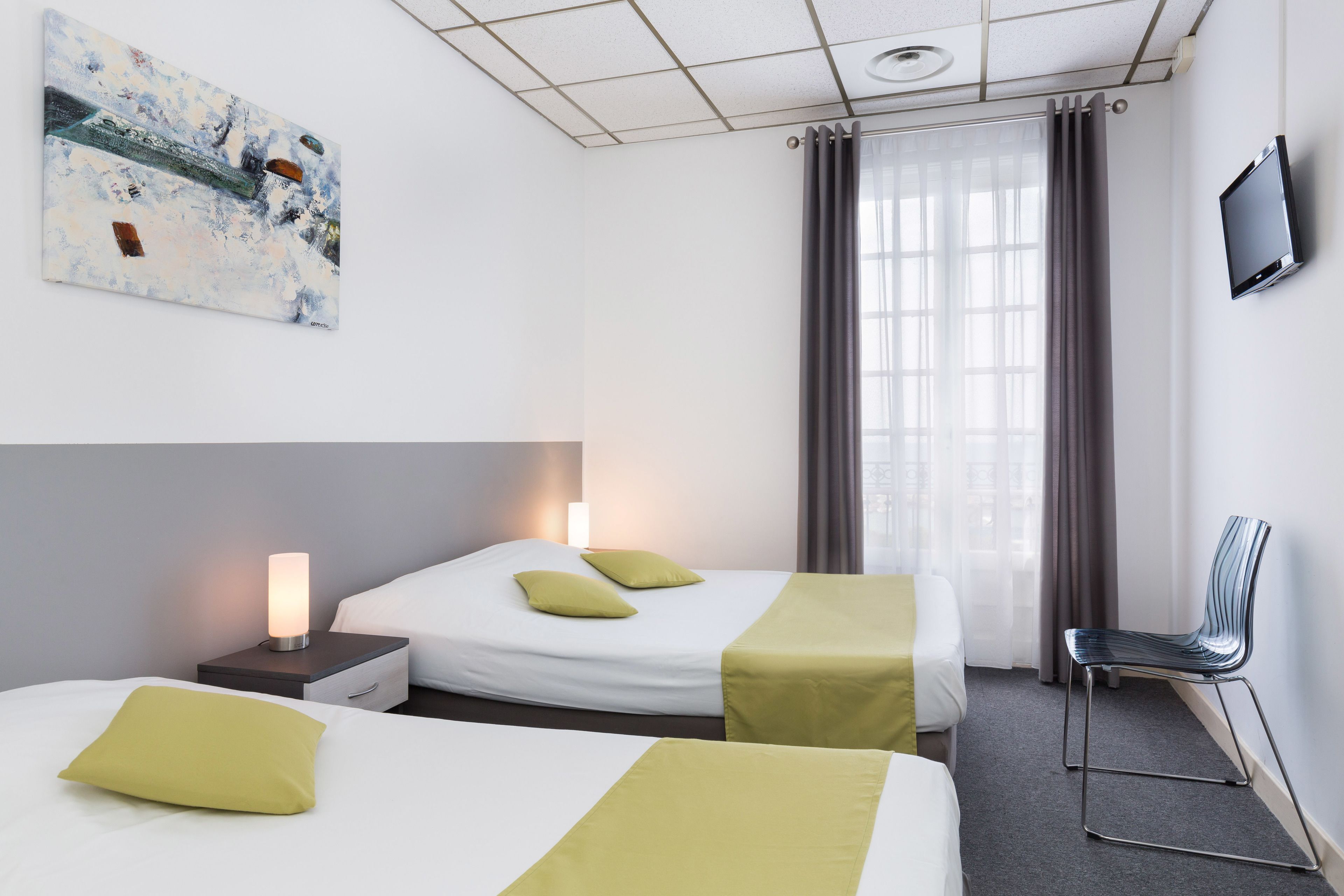 Une chambre d’hôtel avec deux lits, une télévision, un tableau et une fenêtre avec des rideaux.
