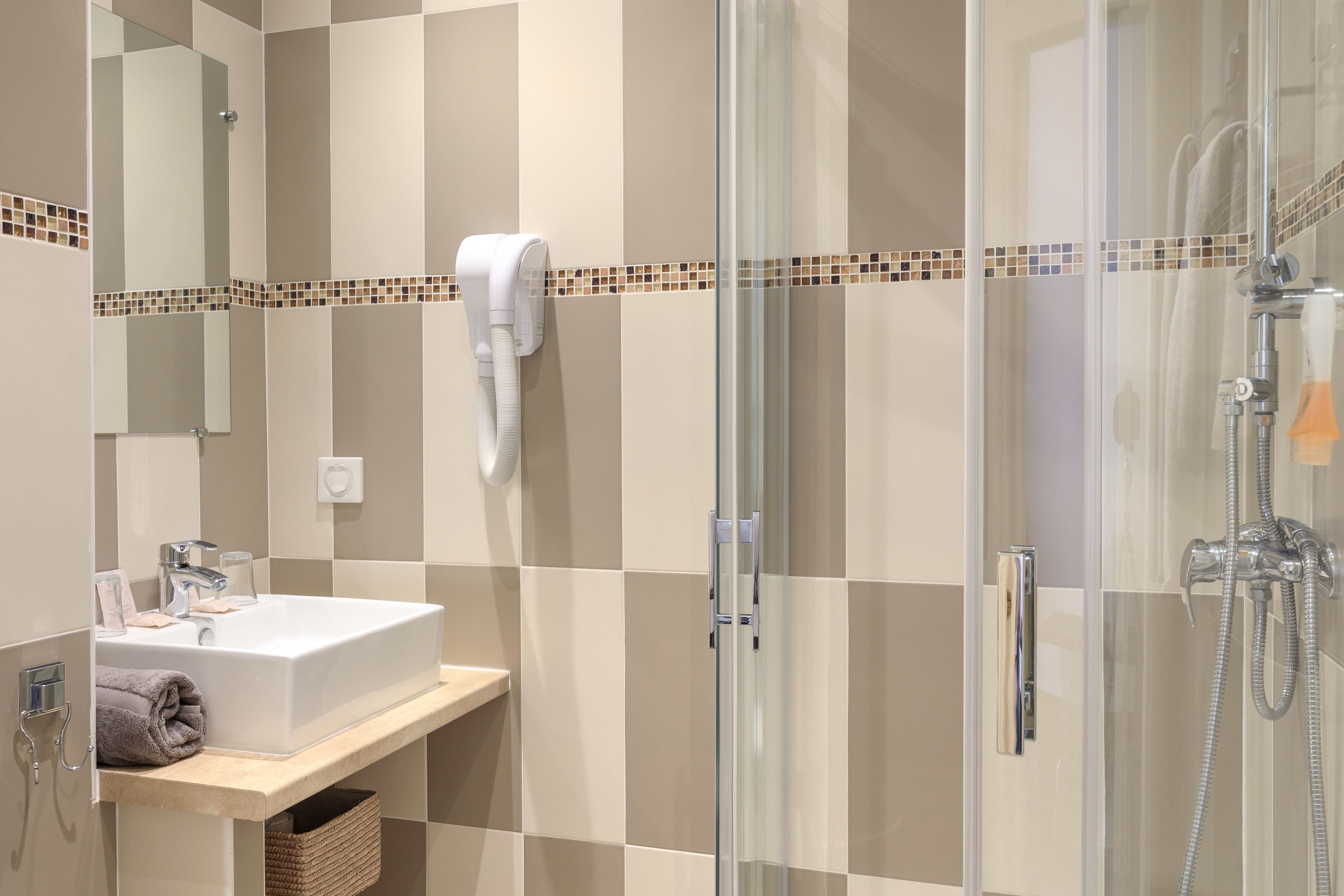 A modern bathroom with a glass-enclosed shower, a white sink, and a towel rack.