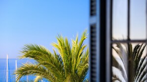 A view of a palm tree and a window with a grid pattern. - Hôtel El Paradiso (Menton)