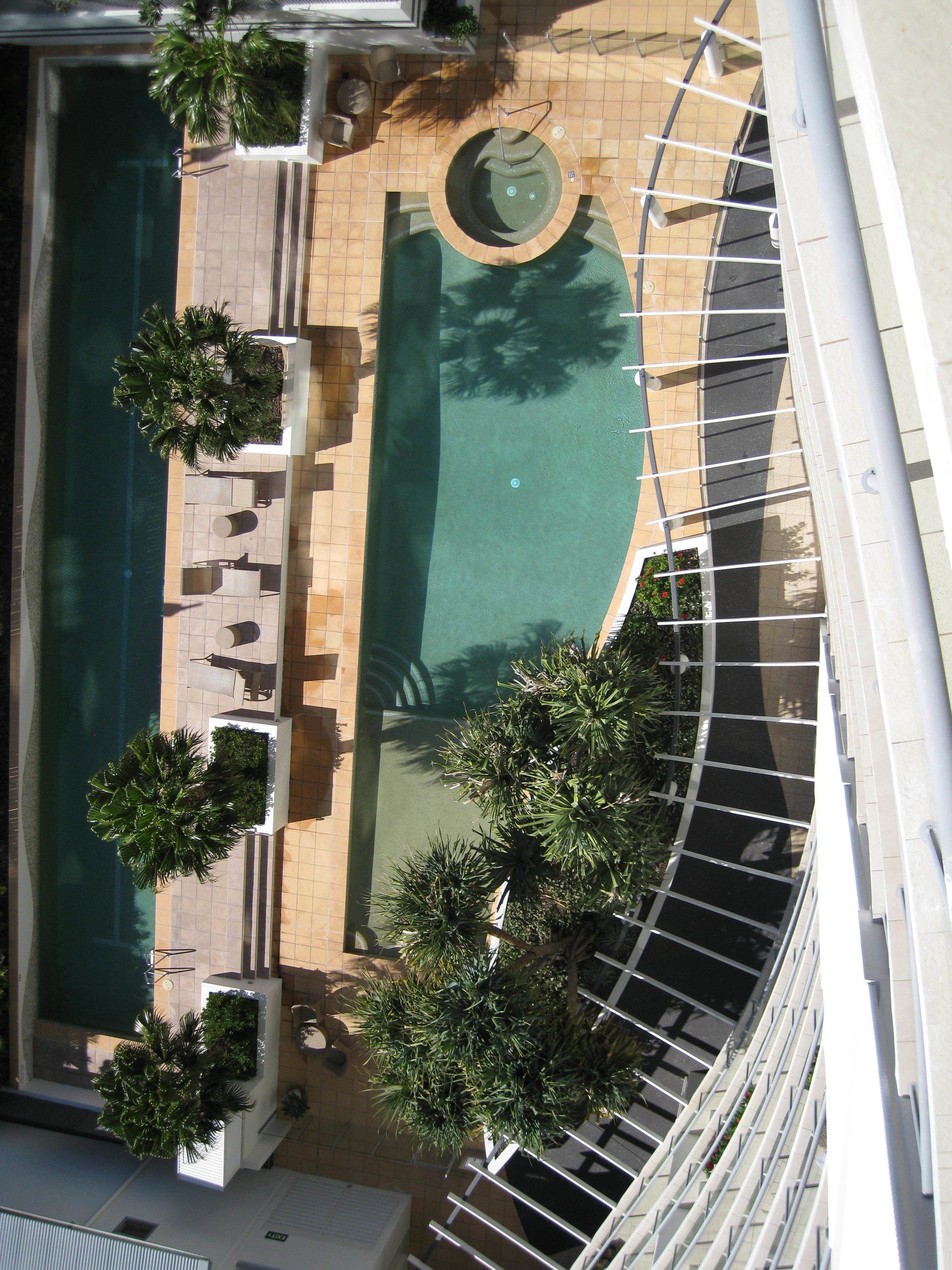 An aerial view of a pool area with a circular hot tub, sun loungers, and potted plants.