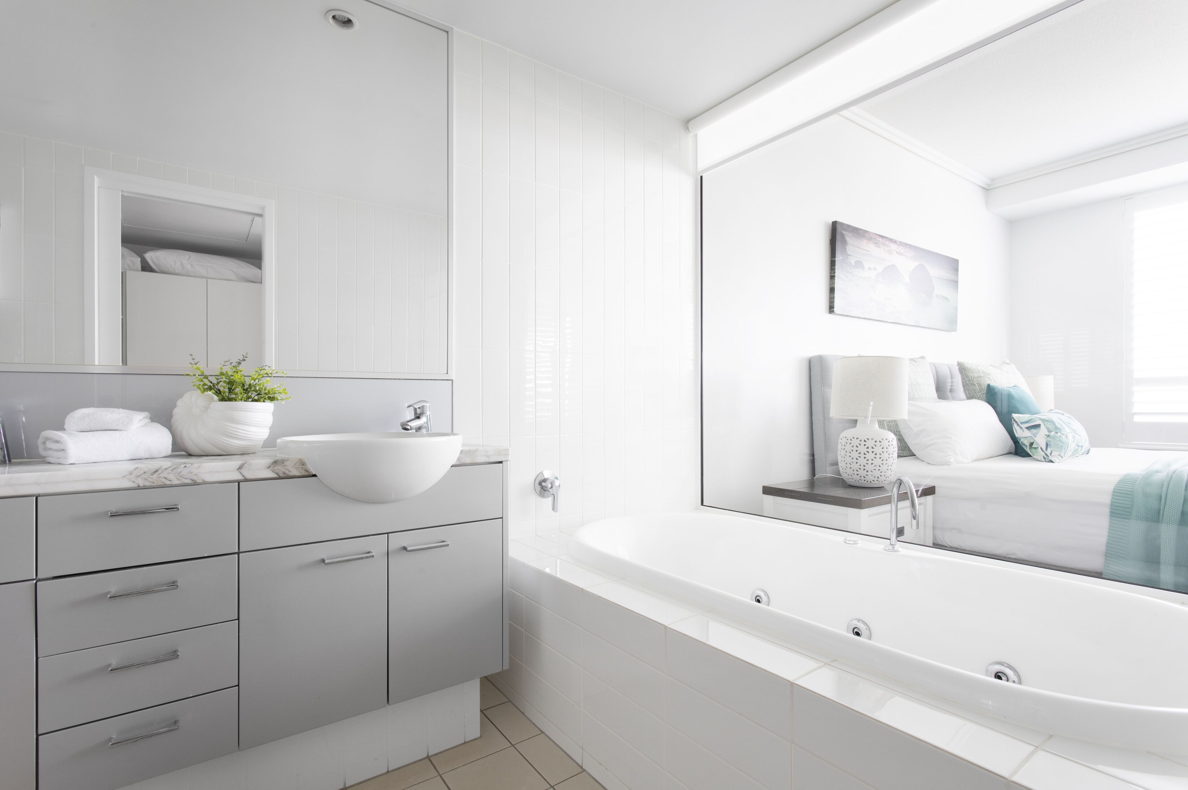 A modern bathroom with a large bathtub, a white sink, and a vanity with drawers.