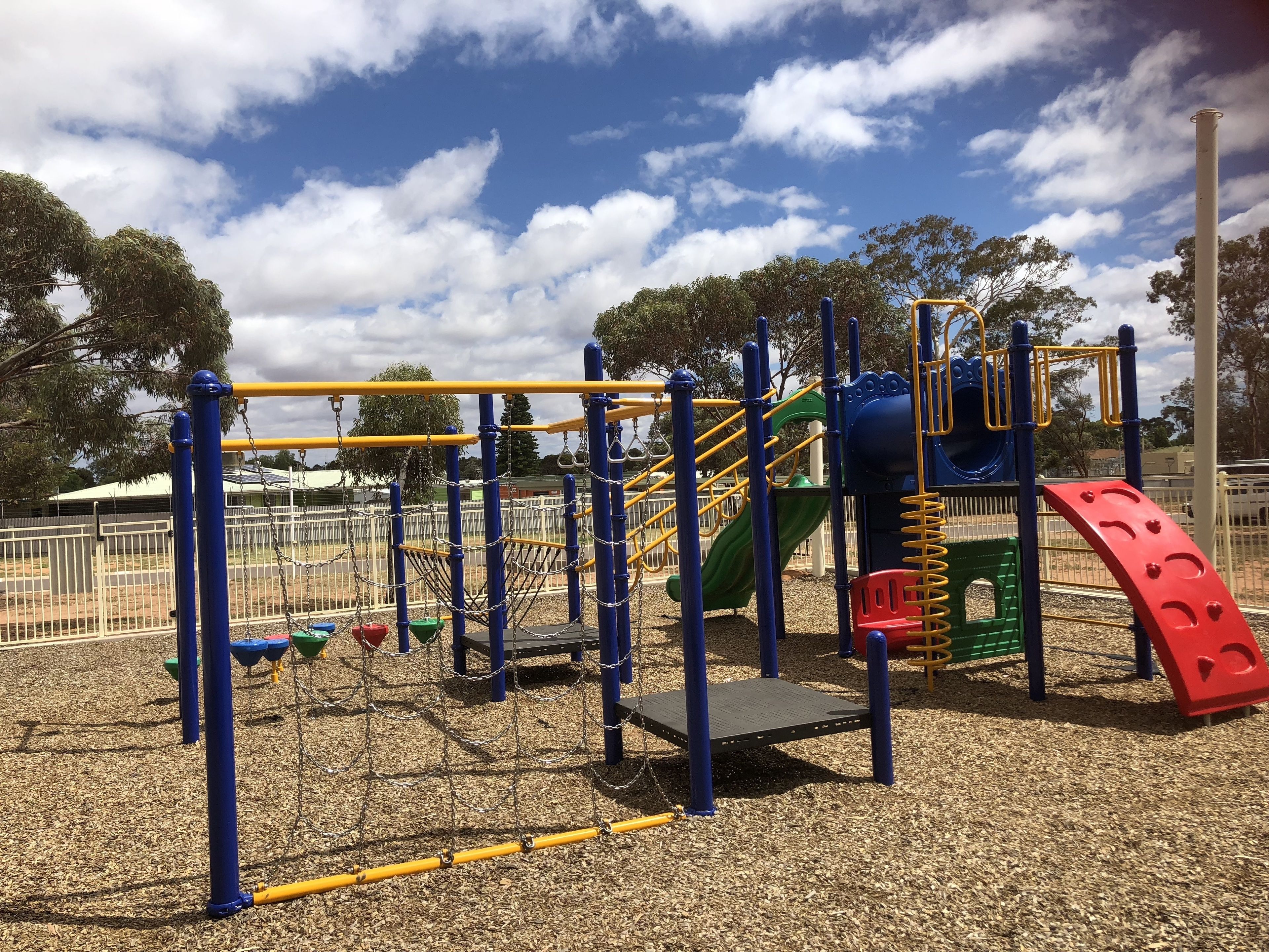 Un parque infantil con estructura para escalar, toboganes y columpios.