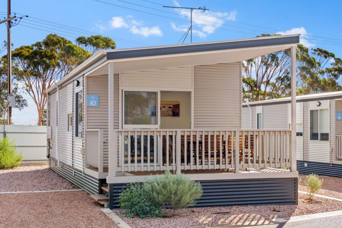A single-story mobile home with a covered porch and a small deck.