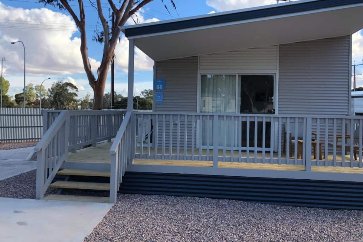 A single-story building with a covered porch, a wheelchair-accessible ramp, and a gravel driveway.