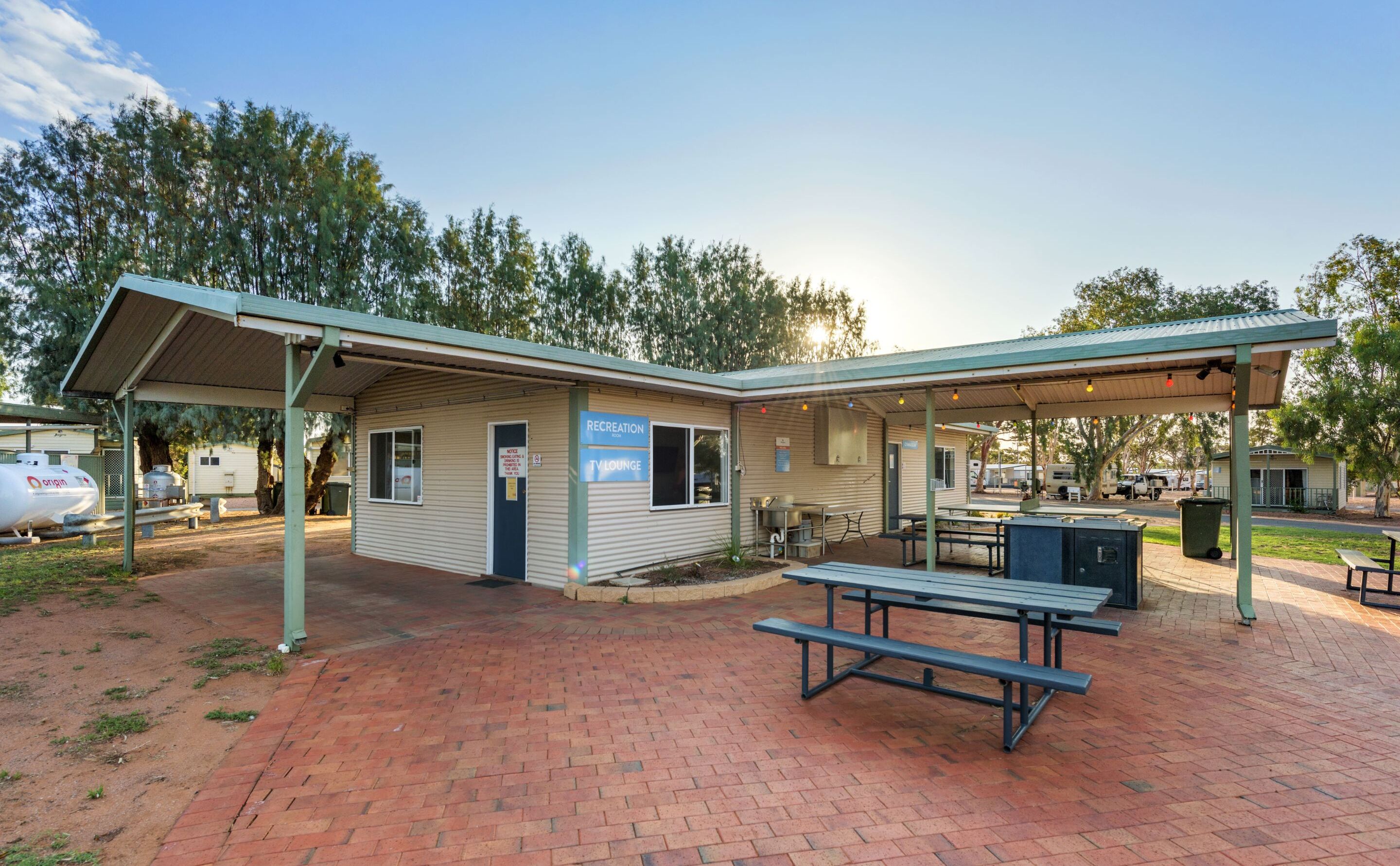 A recreation building with a covered patio, picnic tables, and a TV lounge.
