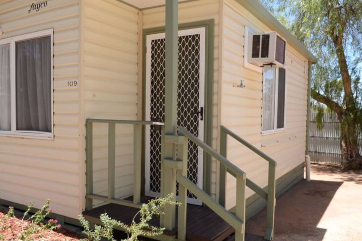 A small, single-story mobile home with a porch and a staircase leading to the entrance.