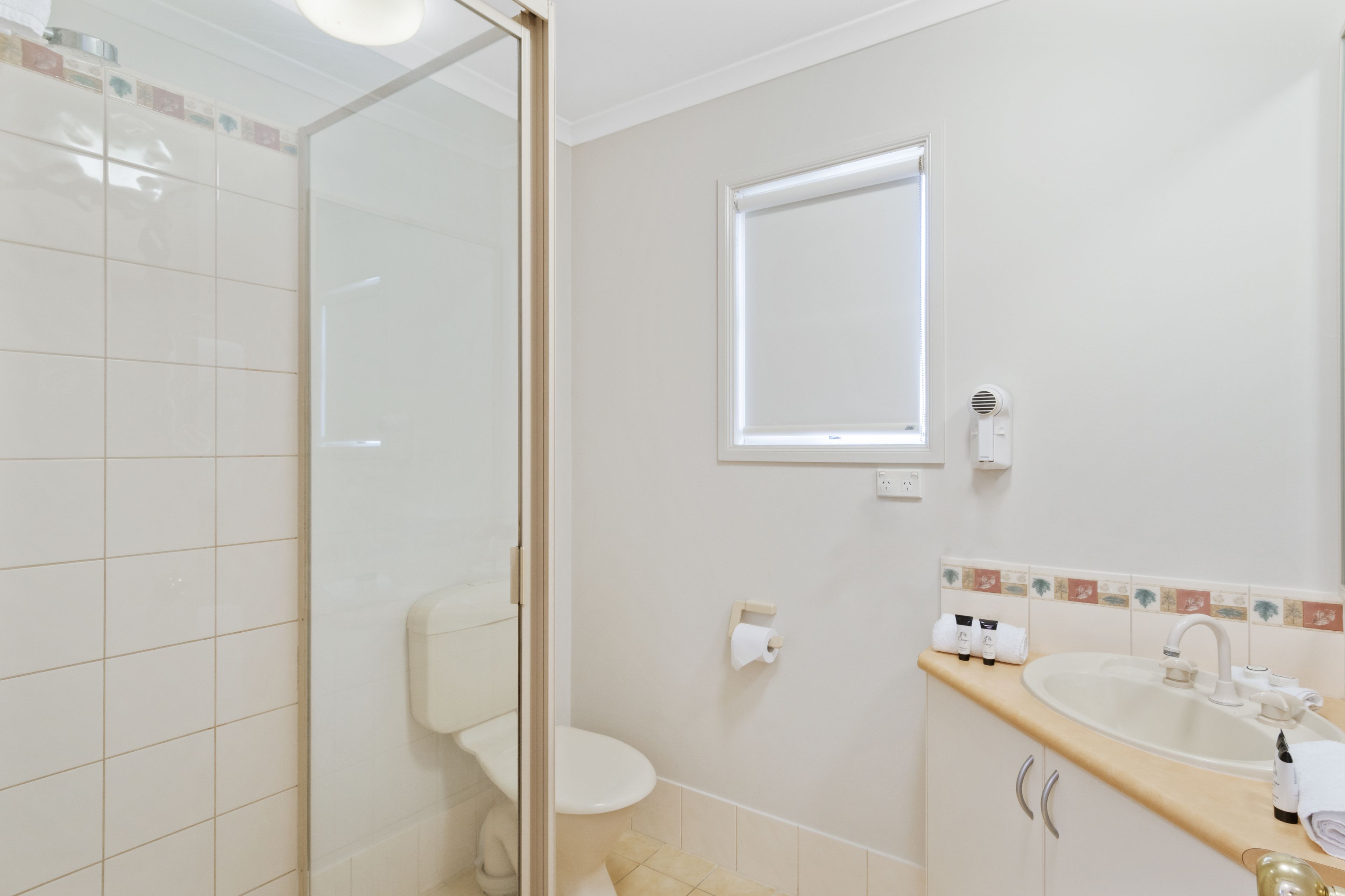 A bathroom with a toilet, sink, and a window.